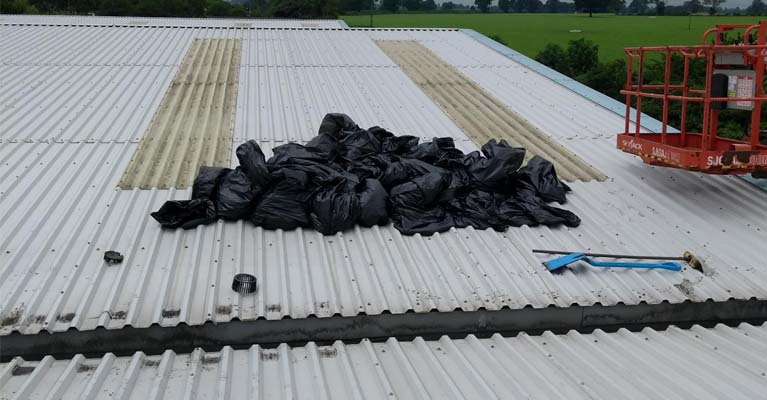 Bagged debris removed from a large warehouse roof during gutter clean-out