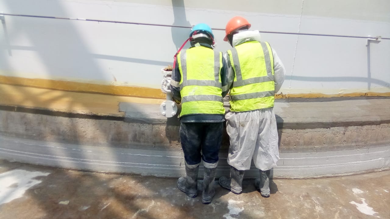 Technicians applying lining to curved tank base
