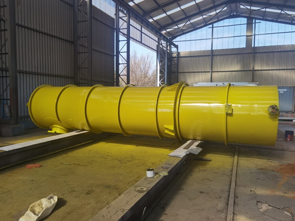 Large fabricated duct section coated bright yellow in workshop