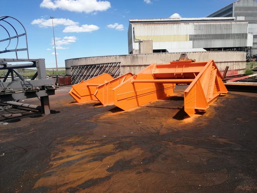Heavy steel chute structure freshly coated in vibrant orange