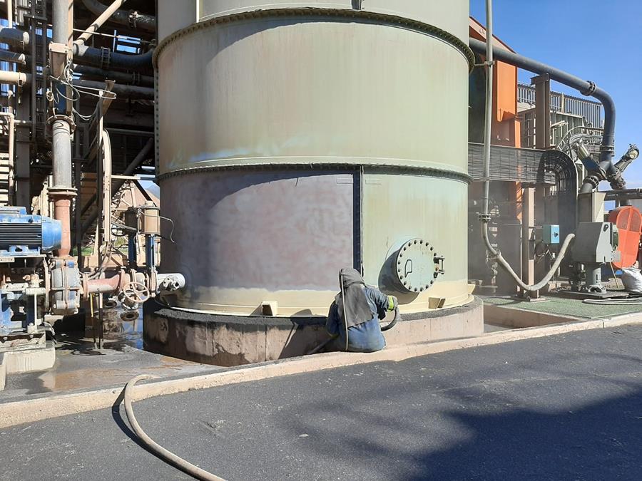 Applicator recoating large process tank base at minerals plant