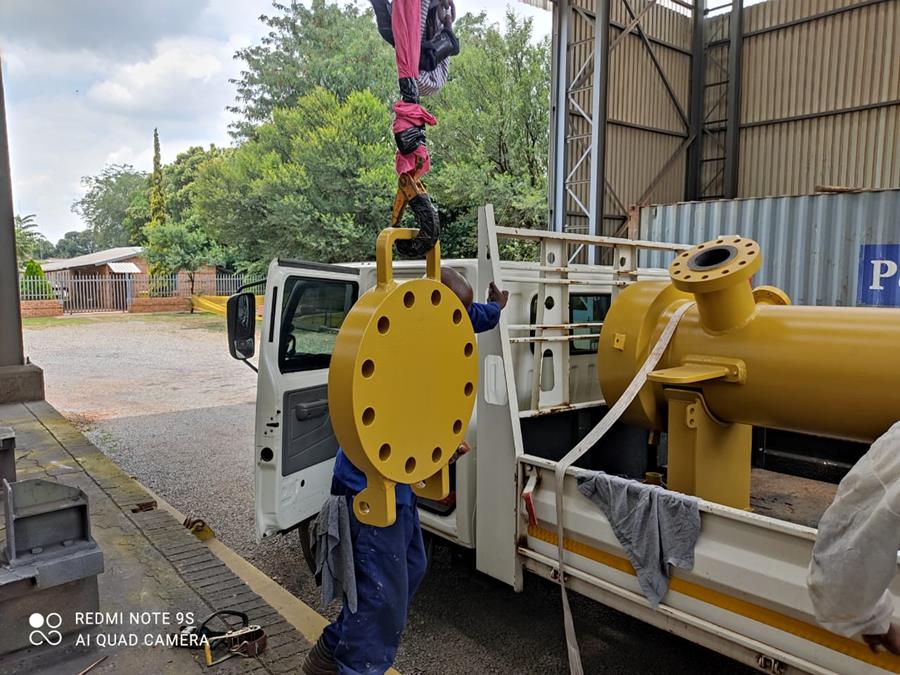 Freshly coated yellow pipeline spool and flange being loaded for delivery