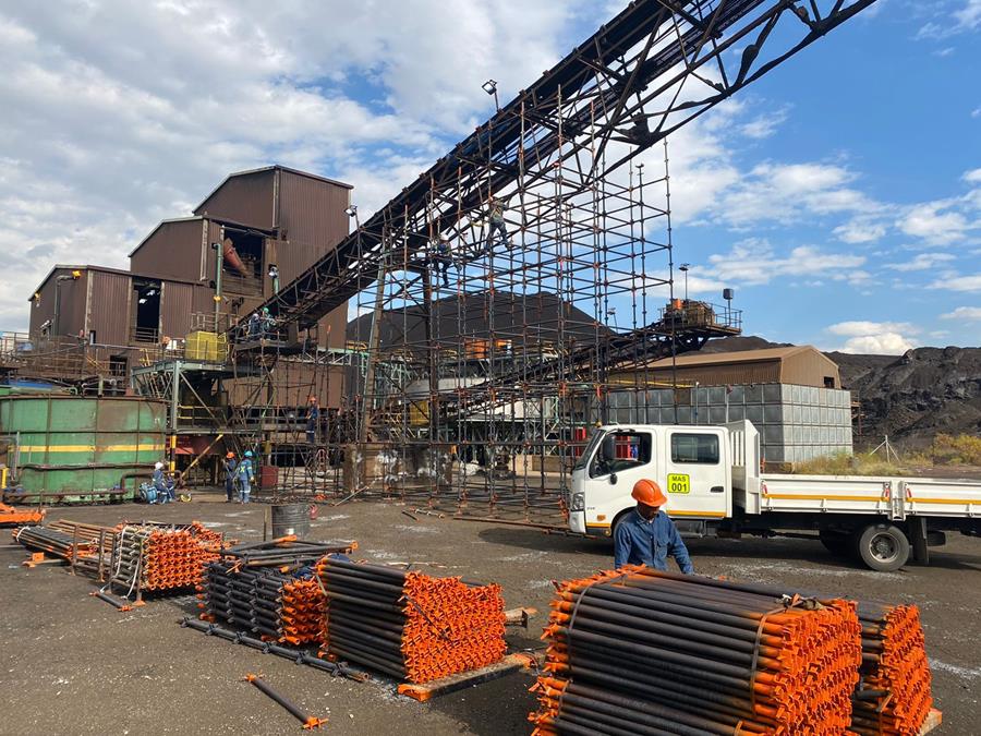 Scaffold erected around conveyor gantry with stacked components on site