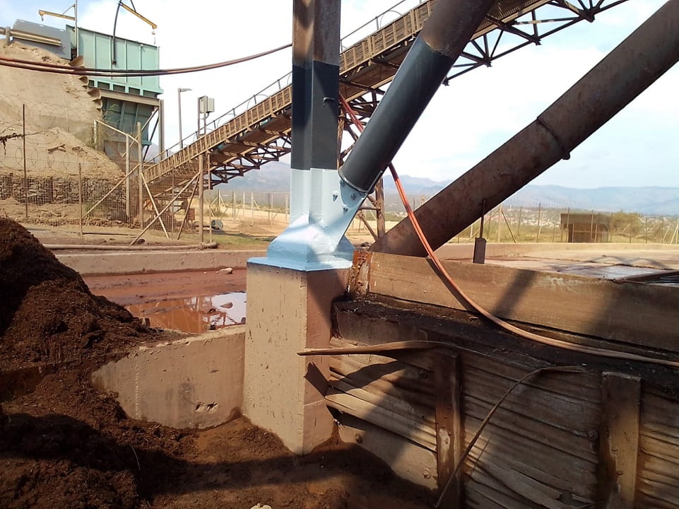 Coated column baseplate adjacent to conveyor and settling pond