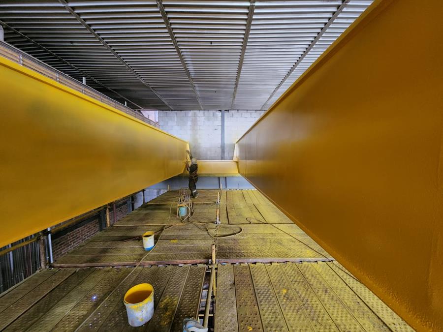 Structural beams freshly coated in vibrant yellow inside industrial building