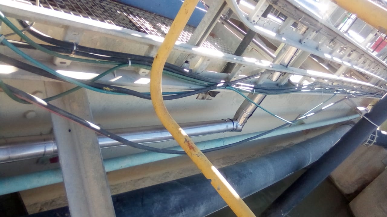 Multiple insulated pipework runs beneath elevated walkway