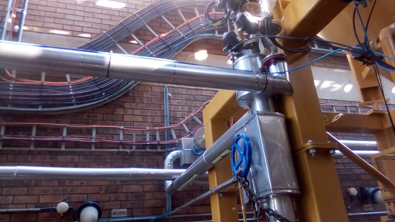 Insulated and clad pipework runs against brick wall in plant room