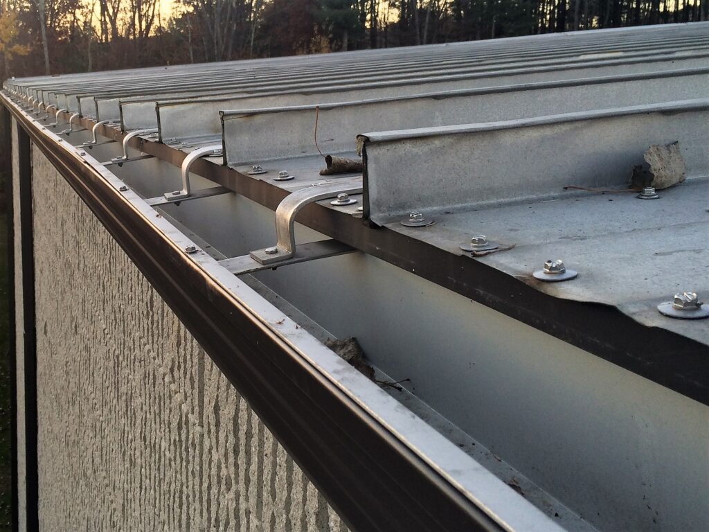 Close-up inspection of gutter brackets and outlets during maintenance